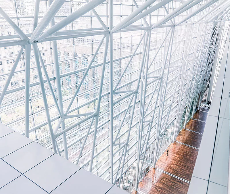 Vue intérieure d’un édifice avec des colonnes blanches et plusieurs fenêtres.