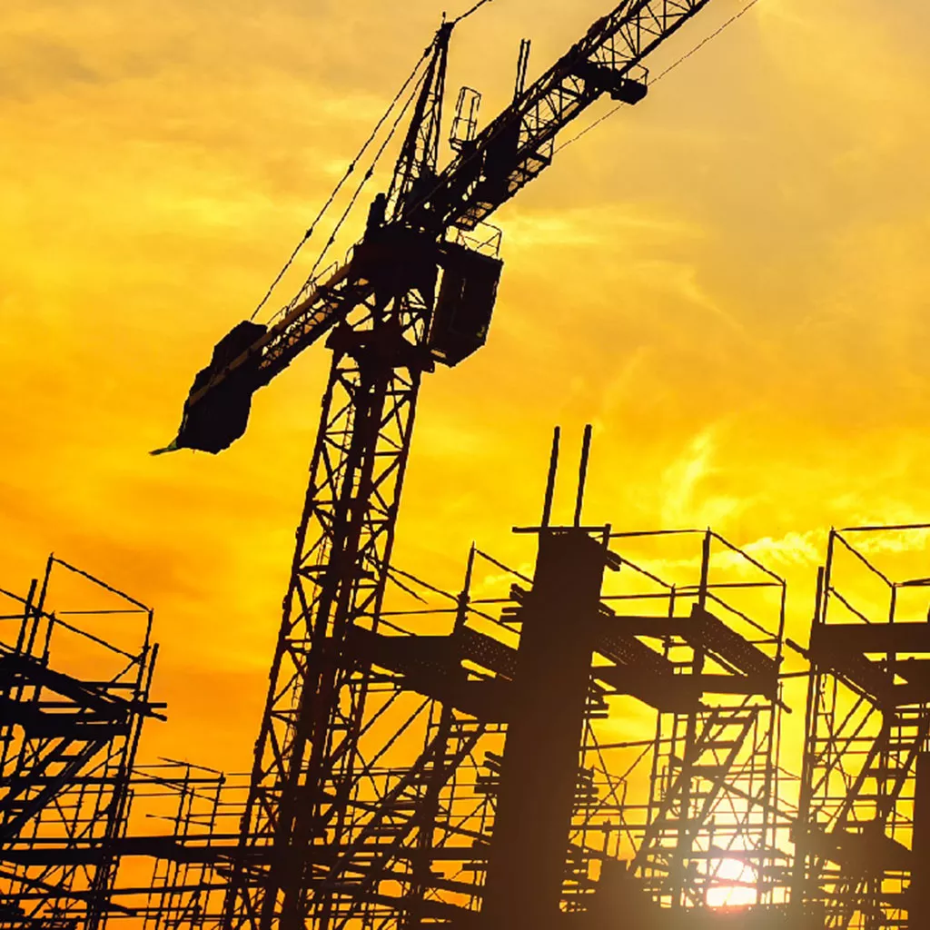 Grue sur chantier de construction au coucher du soleil.