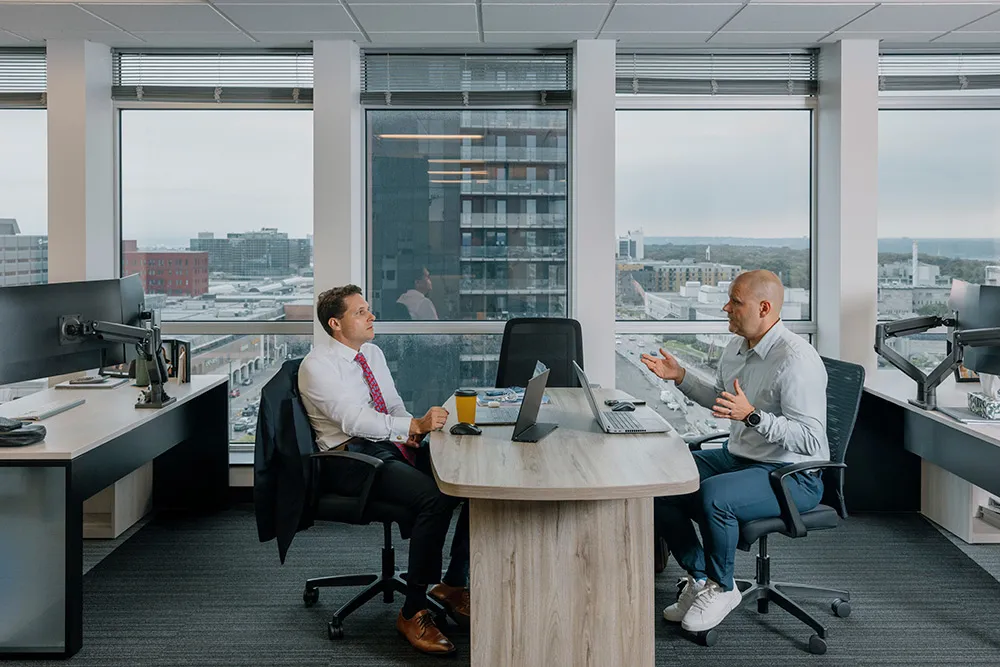 Deux hommes échangent au bureau.